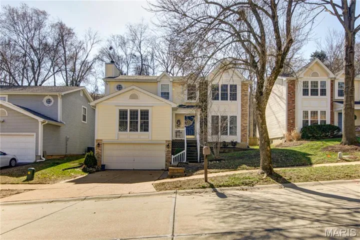Traditional home featuring concrete driveway, a chimney, brick siding, and a garage