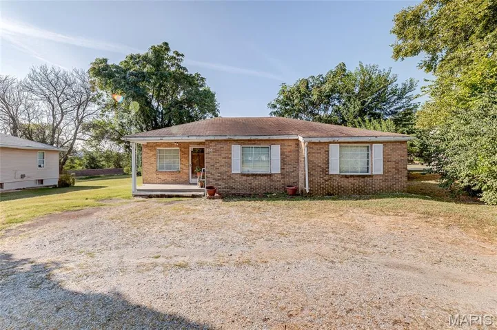 View of front of home with brick siding, a shingled roof, a front yard, and a porch
