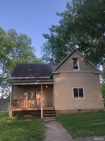View of front facade featuring covered porch, a front yard, a chimney, and crawl space