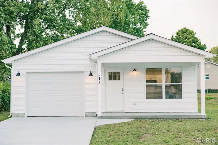 Ranch-style home with covered porch, concrete driveway, a garage, and a front lawn