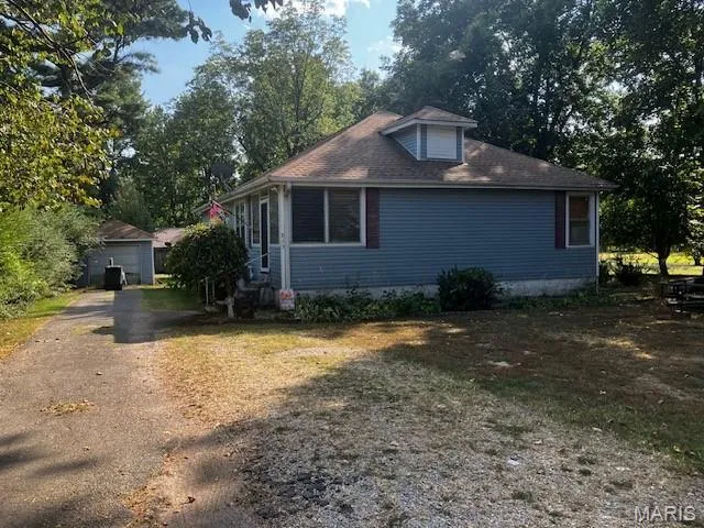 View of front of home with an outdoor structure, a garage, and driveway