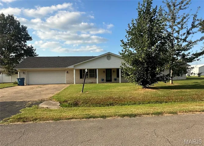 Ranch-style home with brick siding, concrete driveway, covered porch, and a front lawn