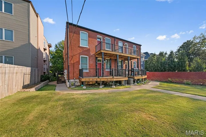 Rear view of property featuring a balcony and brick siding