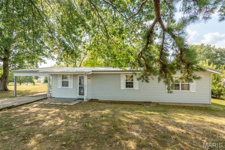 Rear view of property featuring a carport, a yard, and a patio area