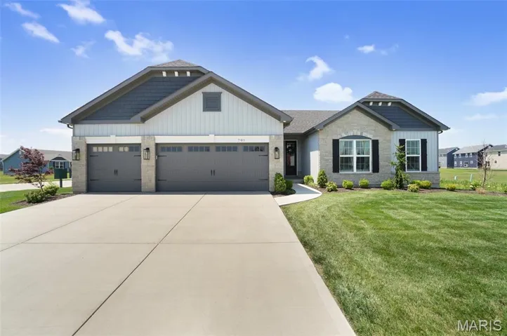 Craftsman house featuring board and batten siding, stone siding, a front yard, and driveway