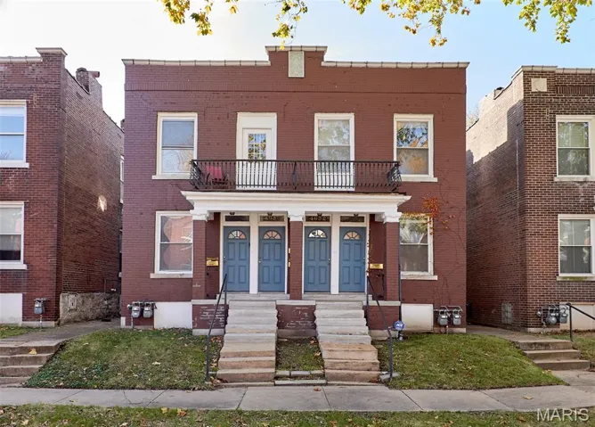 View of front of house with brick siding and a balcony