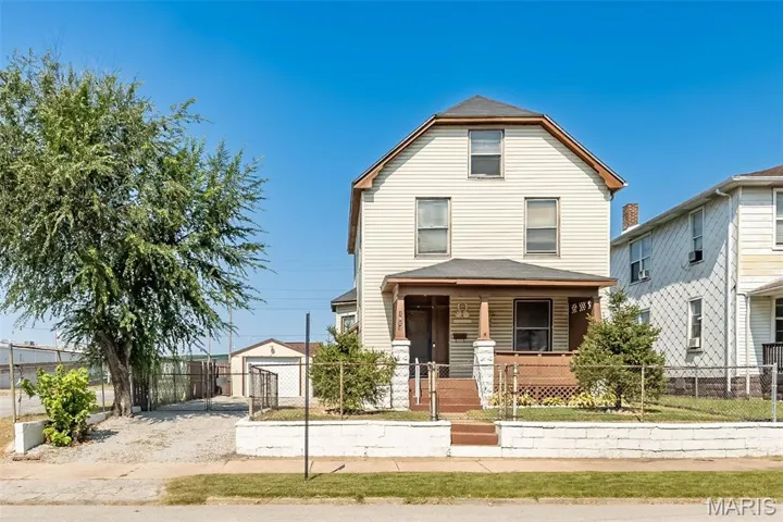 View of front of property with covered porch, an outdoor structure, and a fenced front yard