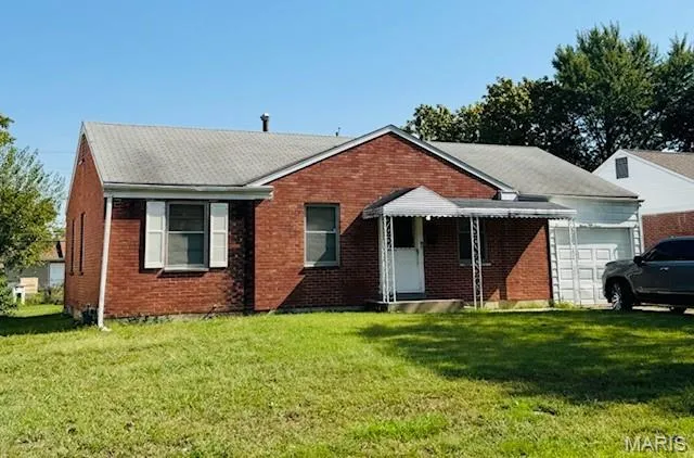 View of front of property featuring a front lawn, brick siding, and a garage