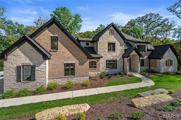 French country home featuring stone siding, a shingled roof, and brick siding