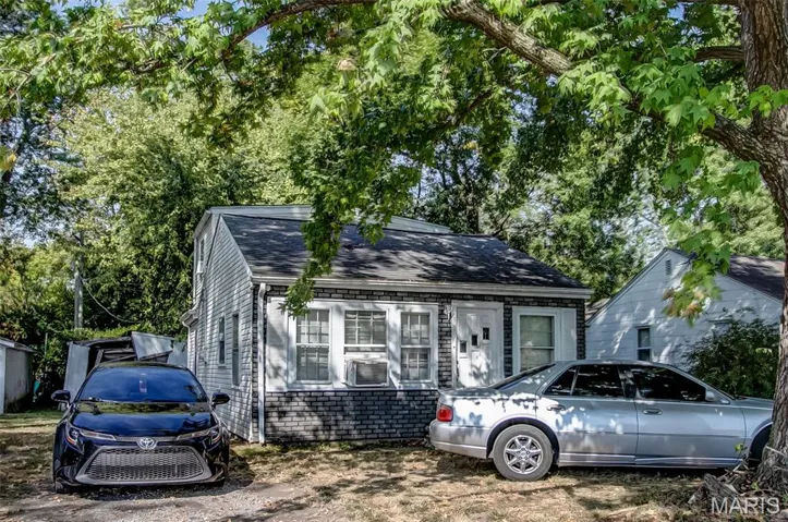 View of front of home with roof with shingles, brick siding, and view of scattered trees