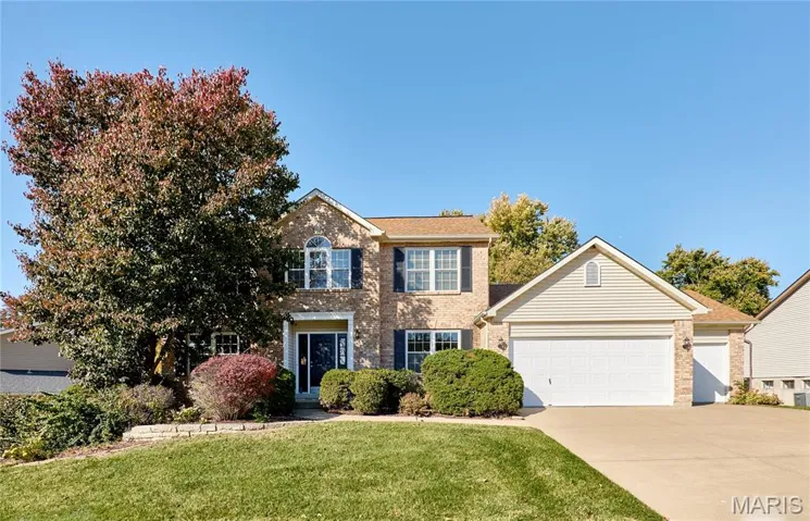 View of front of property with brick siding, a front lawn, driveway, and an attached garage
