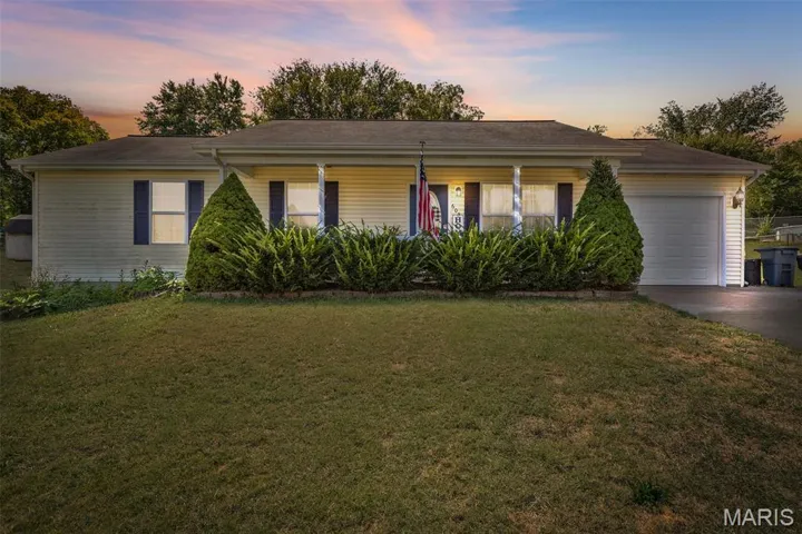 Ranch-style house featuring a front lawn, covered porch, an attached garage, and concrete driveway