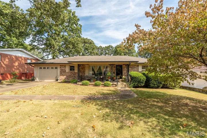 Ranch-style home with a porch, a front lawn, driveway, a garage, and brick siding