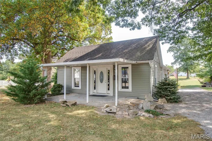 Bungalow-style home featuring covered porch, a front lawn, and a shingled roof