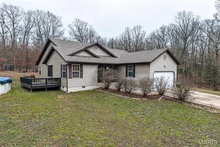 View of front of home featuring a shingled roof, crawl space, a front yard, a wooden deck, and driveway