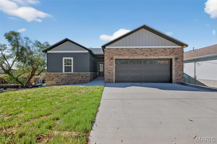 Ranch-style house with concrete driveway, a front lawn, a garage, and brick siding