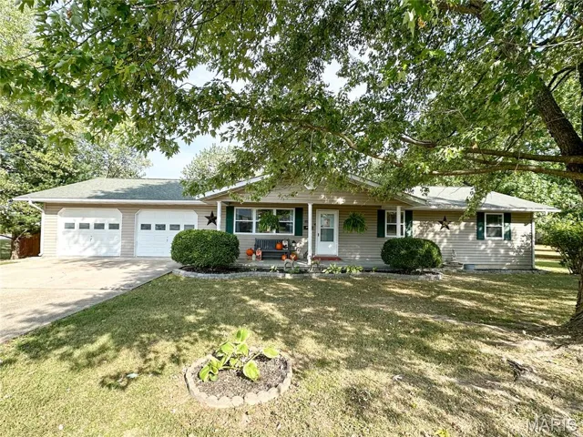 Single story home featuring an attached garage, driveway, a front yard, and a porch