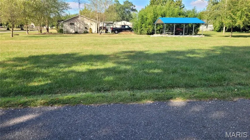 View of green lawn featuring a carport