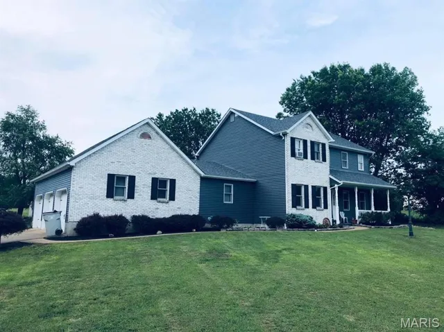 View of front of home featuring a front lawn, brick siding, and a porch