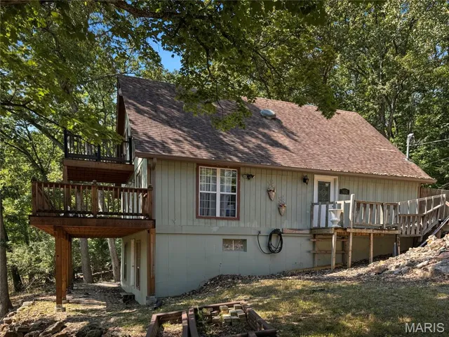 View of front facade with a deck and a shingled roof