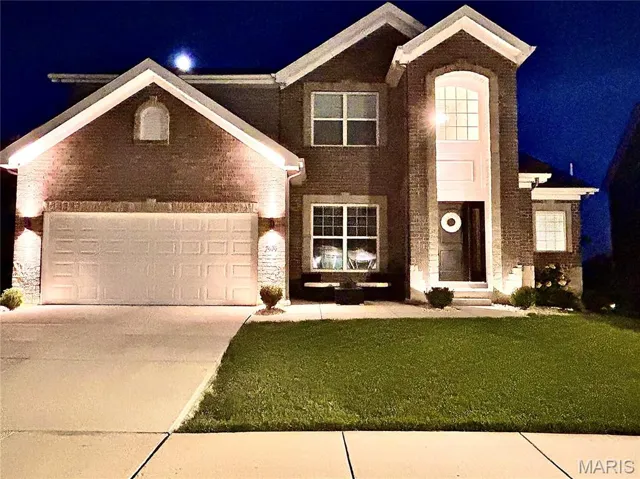 View of front of house featuring concrete driveway, a garage, a yard, and brick siding
