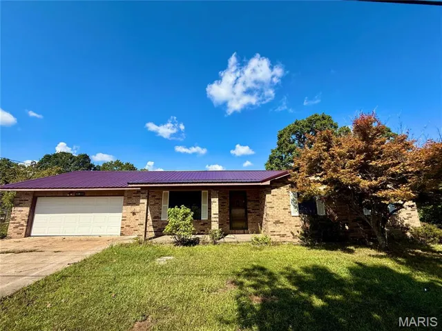 Ranch-style house featuring brick siding, a front lawn, driveway, and covered porch