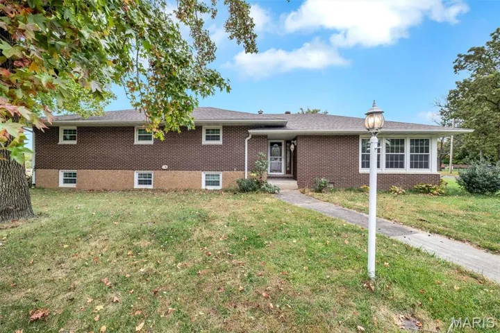 Tri-level home with a front yard and brick siding