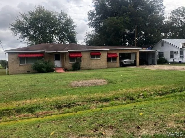 Single story home with brick siding, an attached carport, a front lawn, and driveway