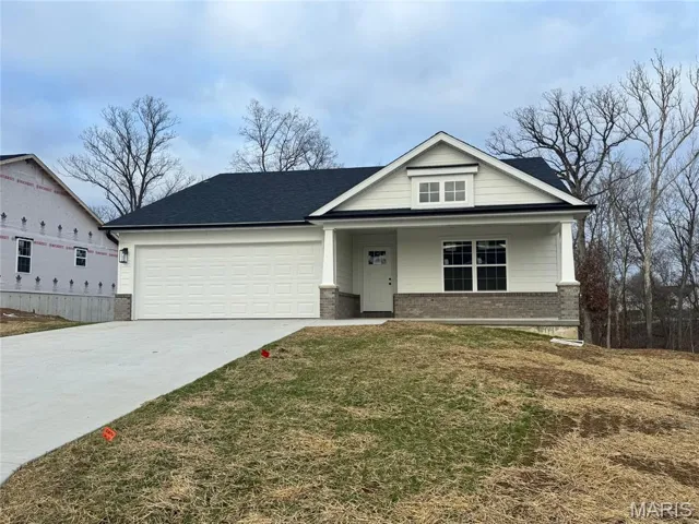 View of front of house featuring brick siding, a porch, driveway, a front lawn, and an attached garage