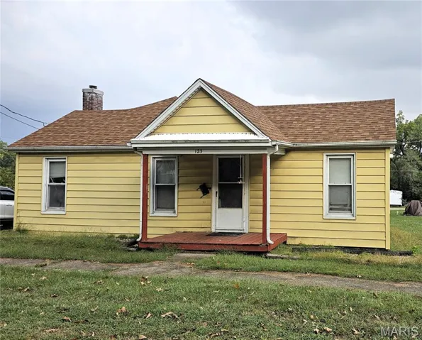 Bungalow-style house with a front yard, a chimney, covered porch, and a shingled roof