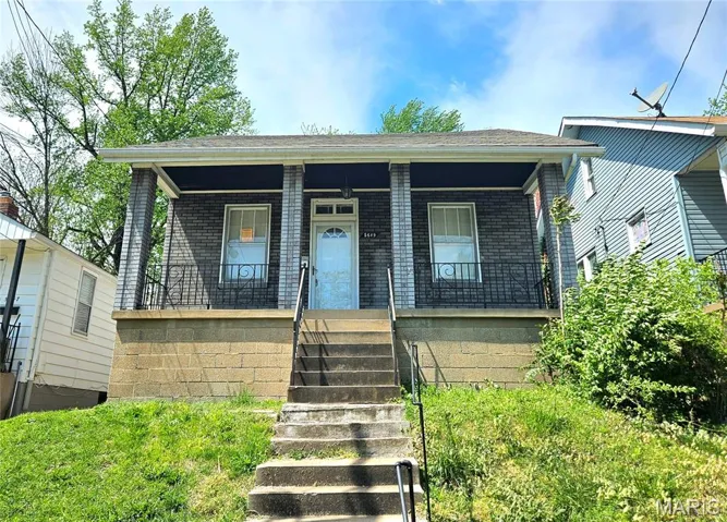 View of front facade with covered porch, brick siding, stairs, and roof with shingles