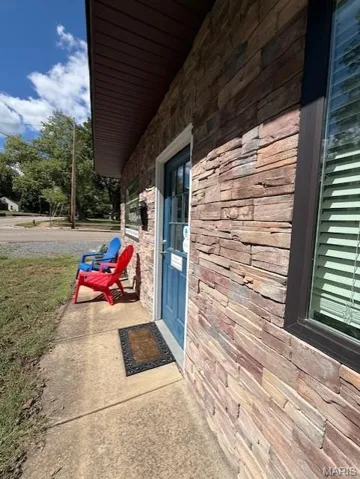 Property entrance featuring a porch and stone siding