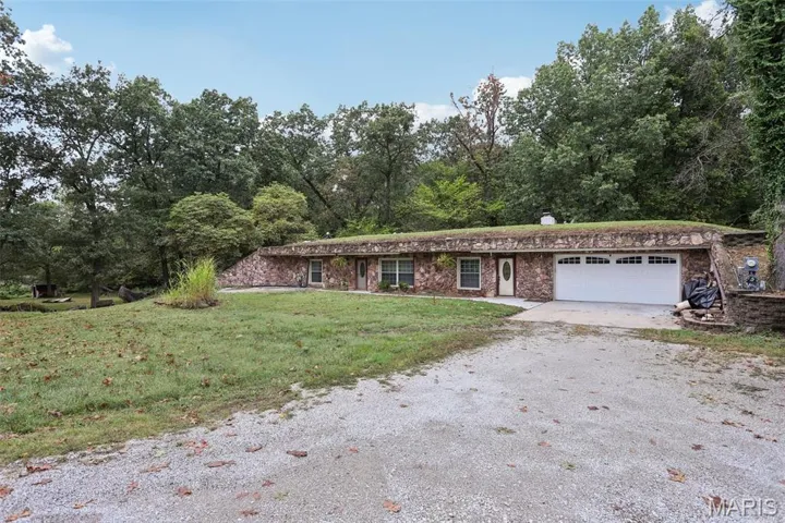 View of front of home featuring driveway, a front yard, and an attached garage