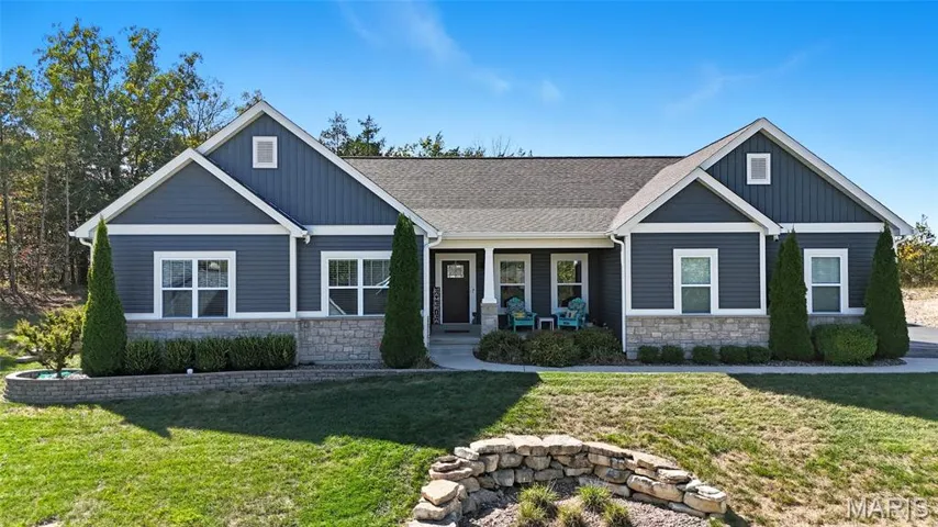 Craftsman-style house with stone siding, covered porch, and a front lawn