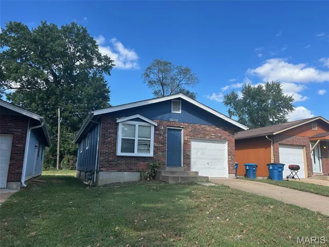 Single story home featuring a front yard, brick siding, concrete driveway, and a garage