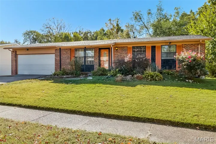 View of front facade with a front yard, brick siding, and a garage