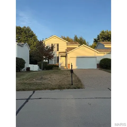 Traditional-style house with brick siding, concrete driveway, an attached garage, and a front yard