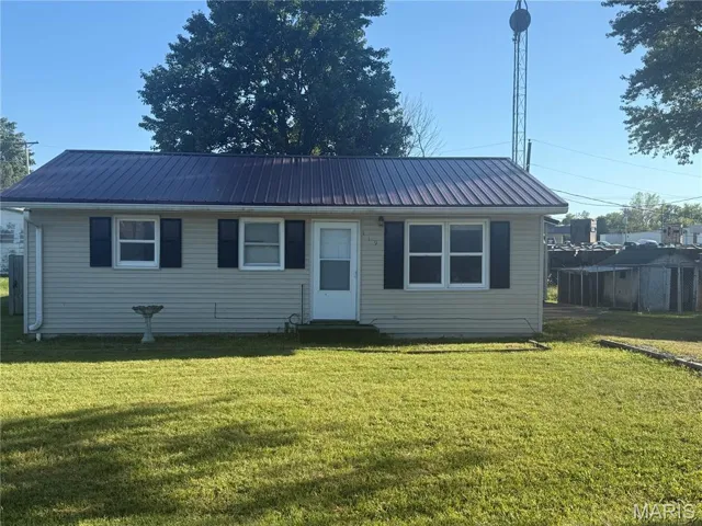 View of front of home with a front yard, a metal roof, and entry steps