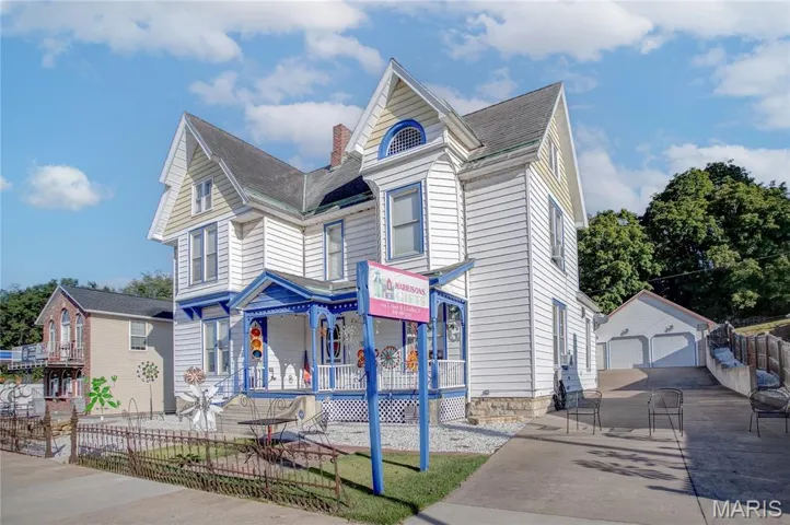 Victorian-style house featuring a garage, an outbuilding, covered porch