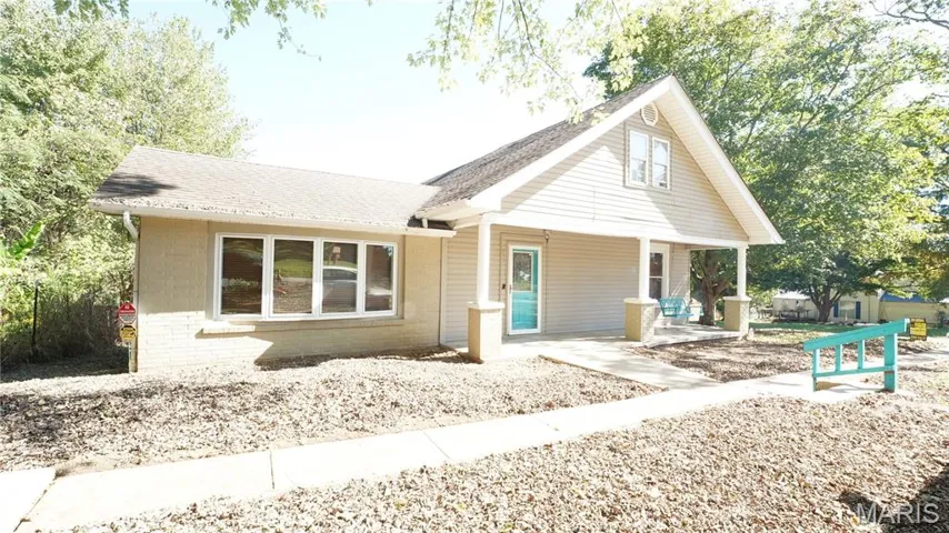 Front of property featuring covered porch, brick siding, and a shingled roof