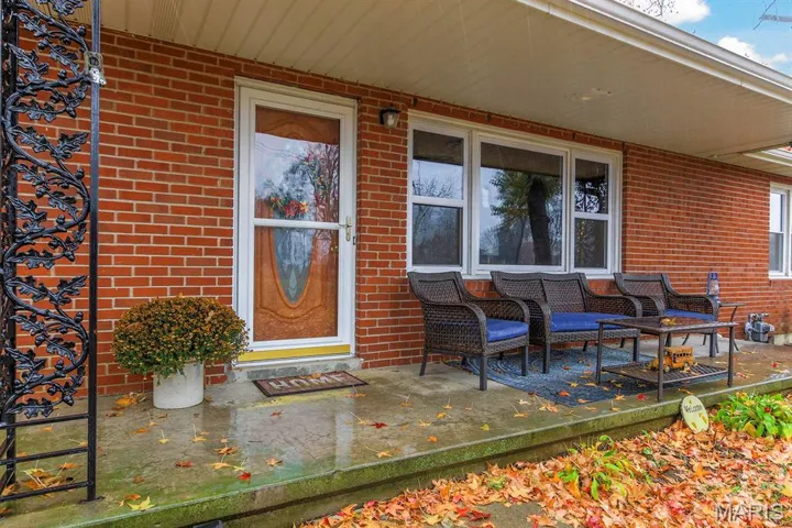 Entrance to property with brick siding and a porch