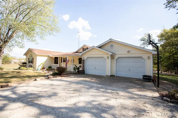 Ranch-style home featuring covered porch, driveway, and an attached garage