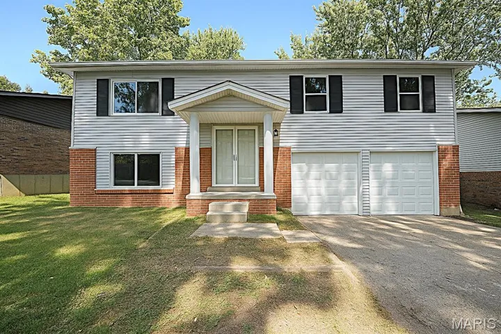 Bi-level home with driveway, an attached garage, a front yard, and brick siding