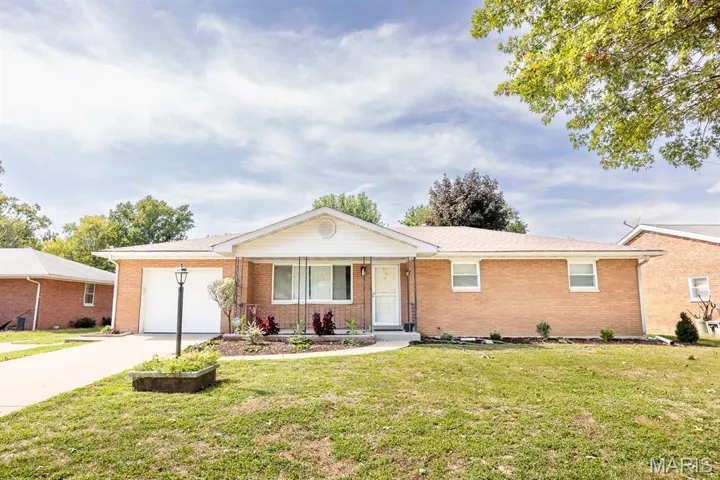 Ranch-style house featuring driveway, covered porch, brick siding, a front lawn, and a garage