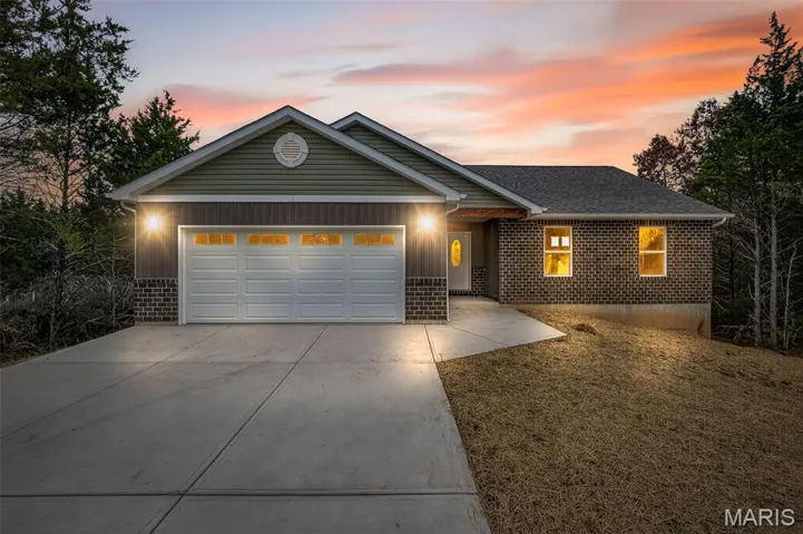 Ranch-style home featuring brick siding, concrete driveway, a garage, and a shingled roof