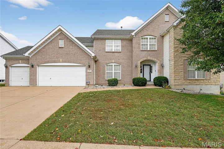 Traditional-style house featuring a front lawn, concrete driveway, a garage, brick siding, and roof with shingles