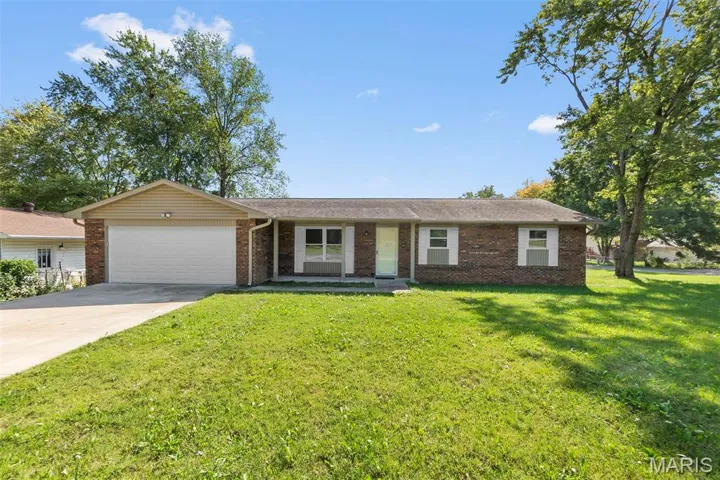 Single story home with brick siding, driveway, a front lawn, an attached garage, and a porch