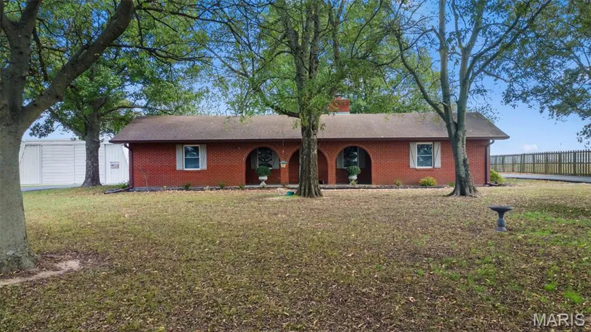 Ranch-style home featuring brick siding, a chimney, and roof with shingles
