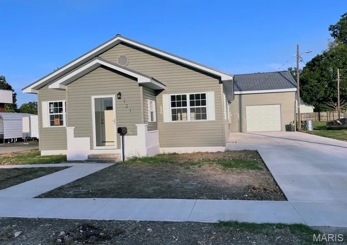 View of front of home featuring concrete driveway, an attached garage, and a metal roof