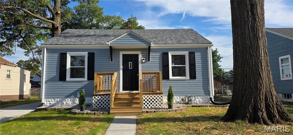 Bungalow-style home with a front yard, a shingled roof, and a chimney